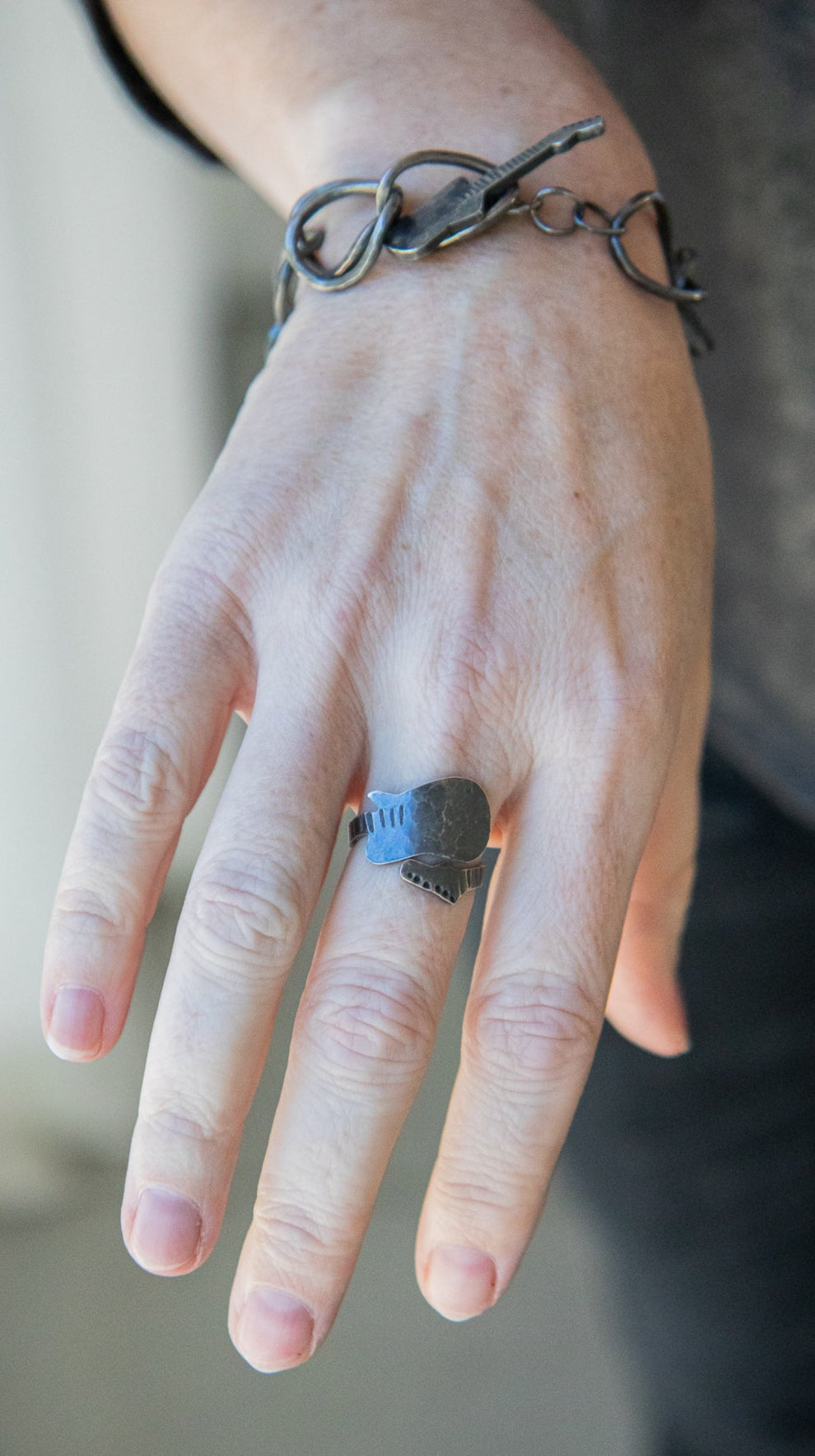 Zilveren armband met een gitaar in de sluiting verwerkt en ring in de vorm van een elektrische gitaar